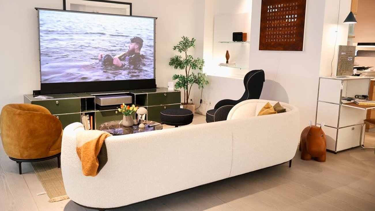 Modern living room with white couch, projector screen, and potted plant