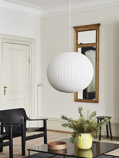 Modernes Wohnzimmer mit runder weißer Hängelampe und schwarzem Möbel-Design