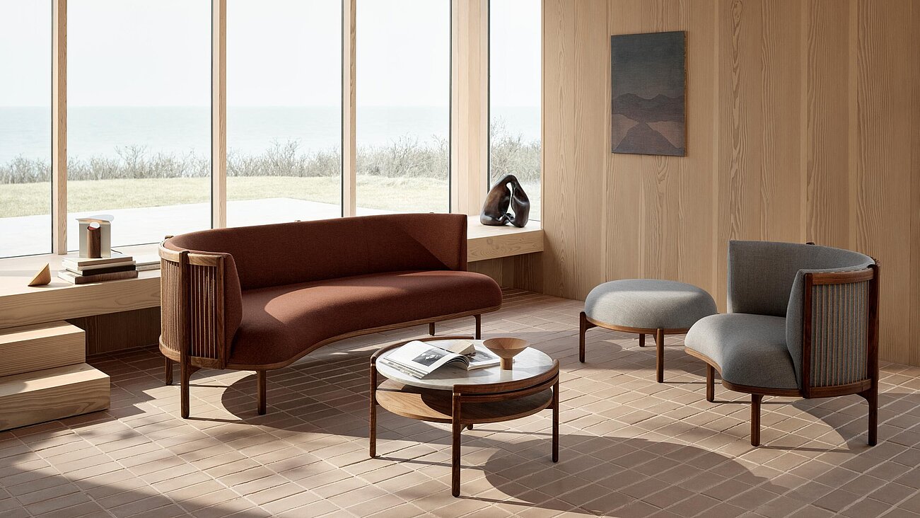 Modernes Wohnzimmer mit Holzverkleidung, Designer-Sofa und Sesseln vor Panoramafenster mit Meerblick
