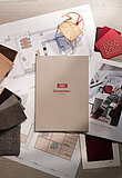 Innenarchitektur-Materialien mit Scheicher-Katalog, Stoffmustern und Grundrissen auf Holzoberfläche