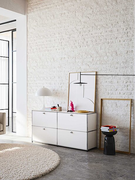 Modernes Wohnzimmer mit weißem Sideboard, Designerlampen und dekorativen Bilderrahmen