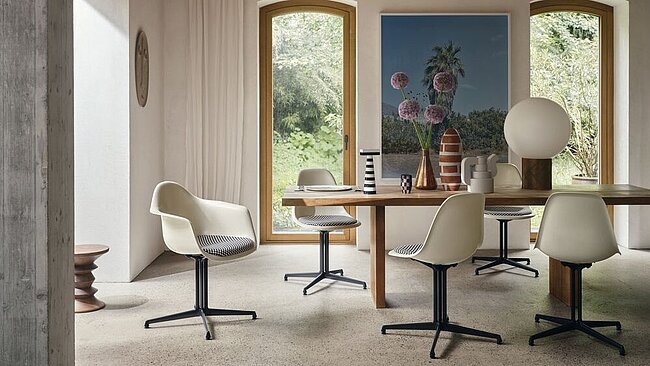 Modernes Esszimmer mit Designerstühlen, Holztisch und großer Fensterfront mit Gartenblick