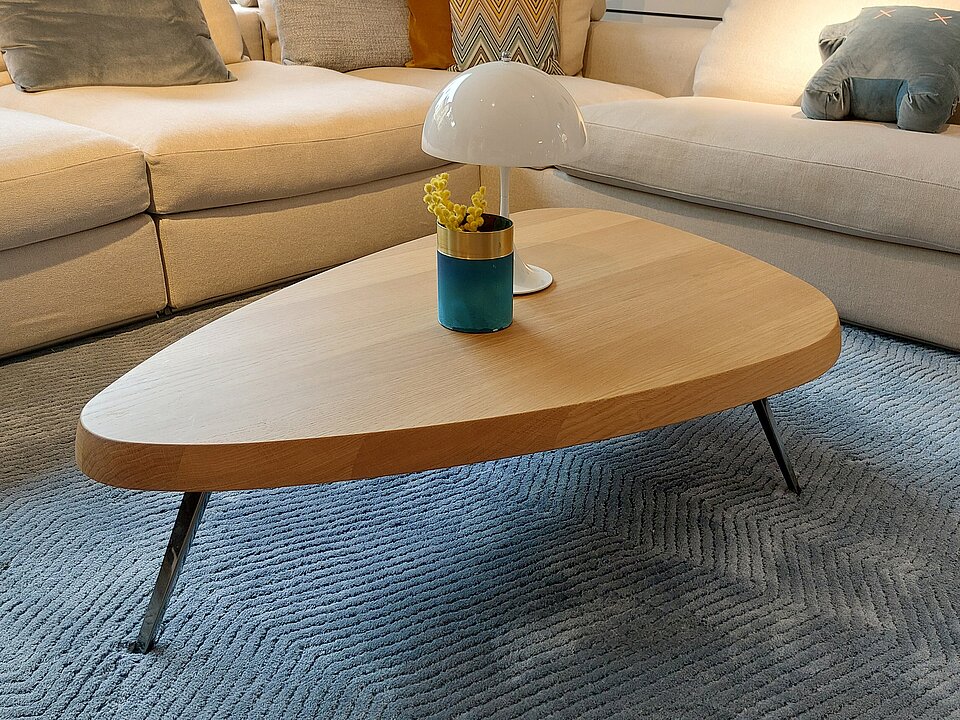 Modernes Wohnzimmer mit hellen Sofas, einem Holz-Couchtisch und Designerlampe auf blauem Teppich