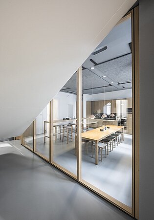 Moderner Konferenzraum mit Holztischen, Glaswänden und minimalistischer Innenarchitektur