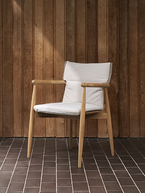 Moderner Holzstuhl mit weißem Polster vor vertikaler Holzverkleidung im minimalistischen Raum