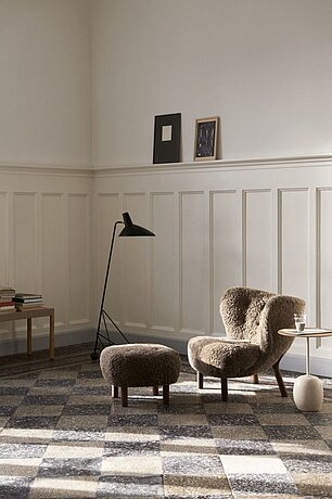 Moderner Sessel mit Hocker und Stehlampe in hellem Wohnzimmer mit Wandvertäfelung