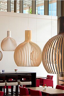 Moderne Holzpendelleuchten über Sitzbereich mit roten Stühlen in einem Café oder Restaurant