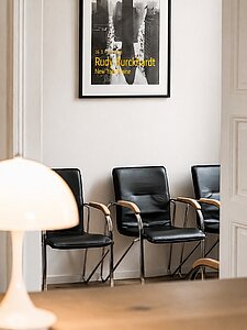 Modern waiting room with black leather chairs and framed cityscape poster