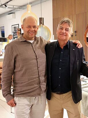 Two men smiling near a modular shelving unit in a modern furniture shop