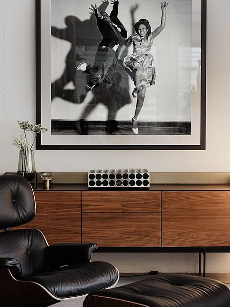 Modernes Wohnzimmer mit Eames Lounge Chair, Holzkommode und großem Schwarzweißfoto an der Wand