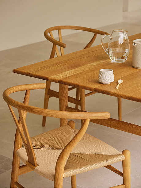 Wooden dining table with glass pitcher, ceramic cup, and two chairs