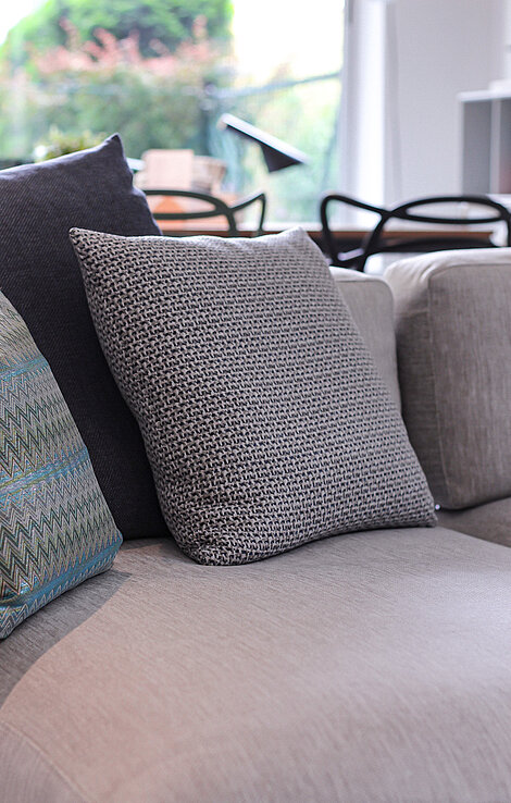 Beigefarbenes Sofa mit dekorativen Kissen vor einem Fenster im modernen Wohnzimmer