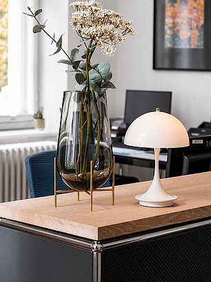 Modern office desk with a white lamp and tall glass vase with flowers
